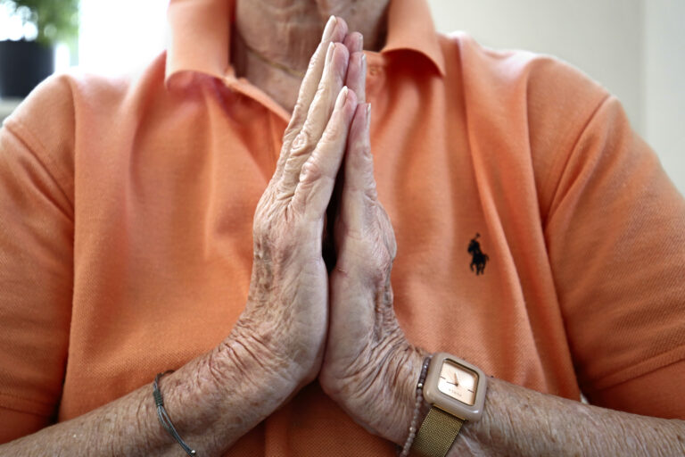 Nahaufnahme von zusammengefalteten Händen vor der Brust beim Seniorenyoga